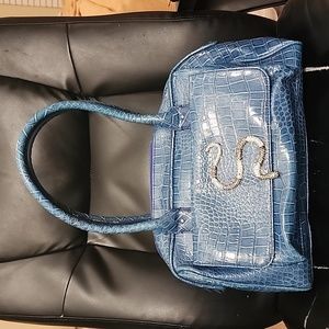 A Paula Abdul blue handbag with a snake on the front of it